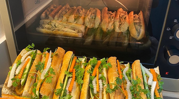 Vietnamese sandwiches in and outside a small oven, filled with vegetables and herbs.