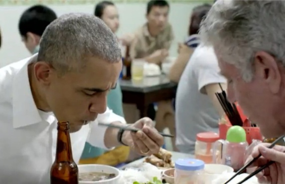 Two people eating with chopsticks in a crowded restaurant.