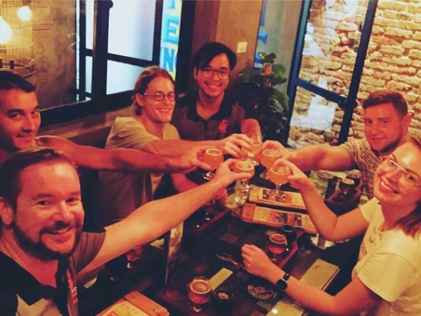 Group of six people sitting at a table, smiling and raising glasses in a toast.