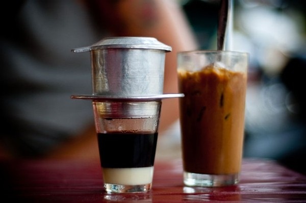 Vietnamese coffee drip filter on glass and iced coffee in tall glass.