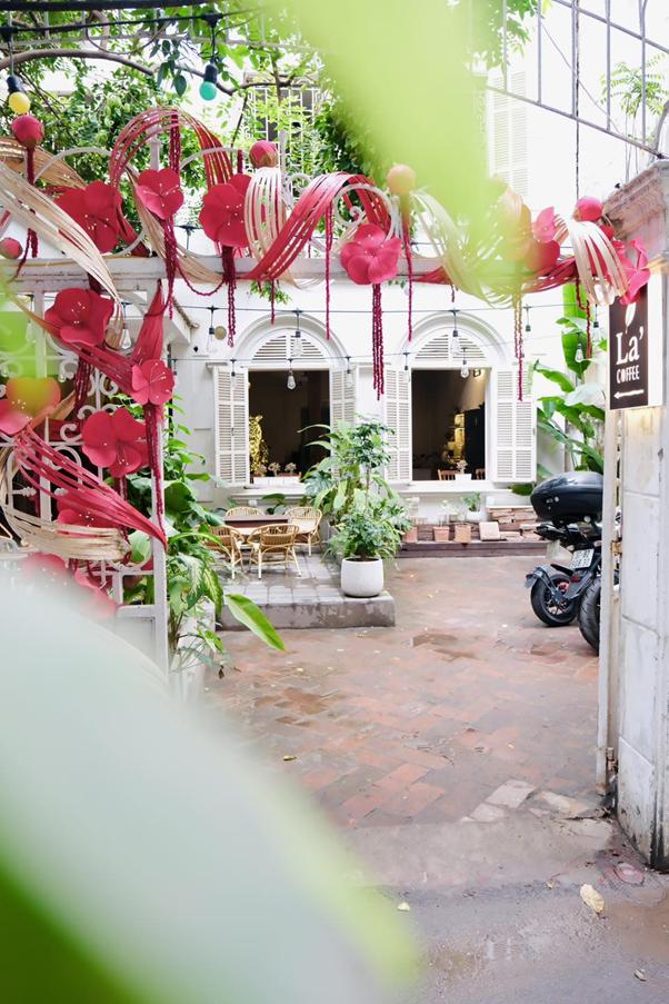 Courtyard with red decorations, plants, tables, and motorbike.