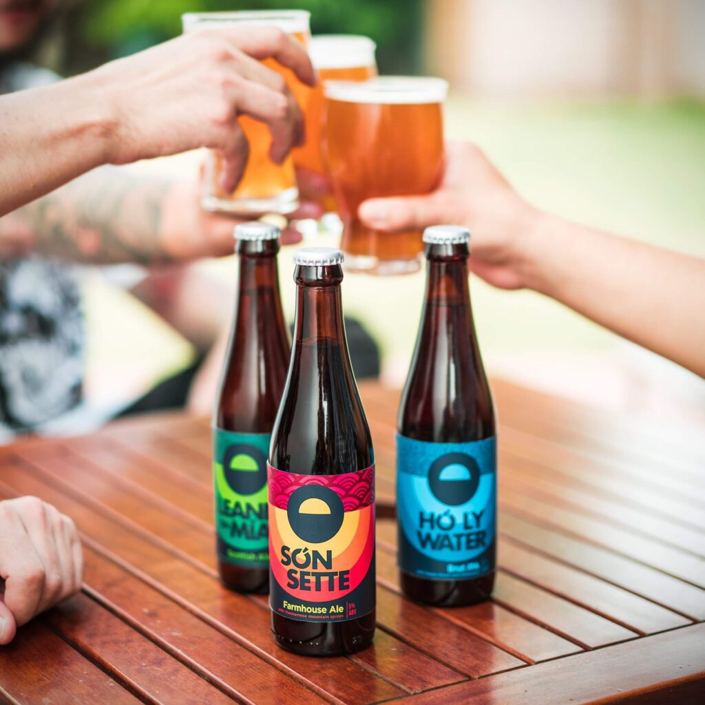 a hand holding a bottle of beer on a table