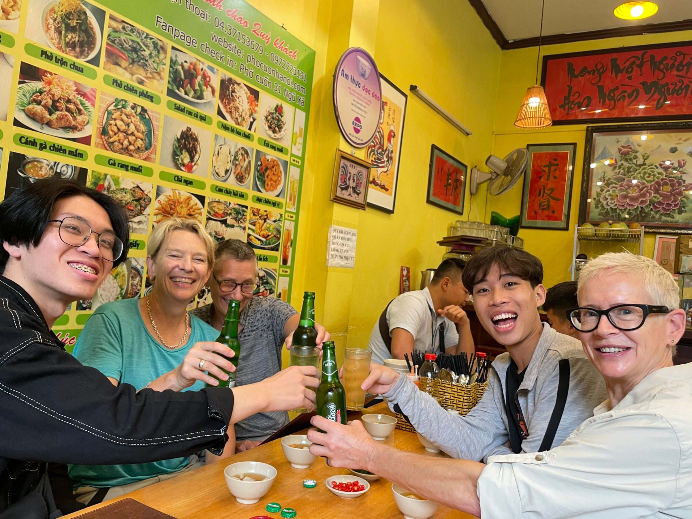 a group of people sitting at a table with a birthday cake