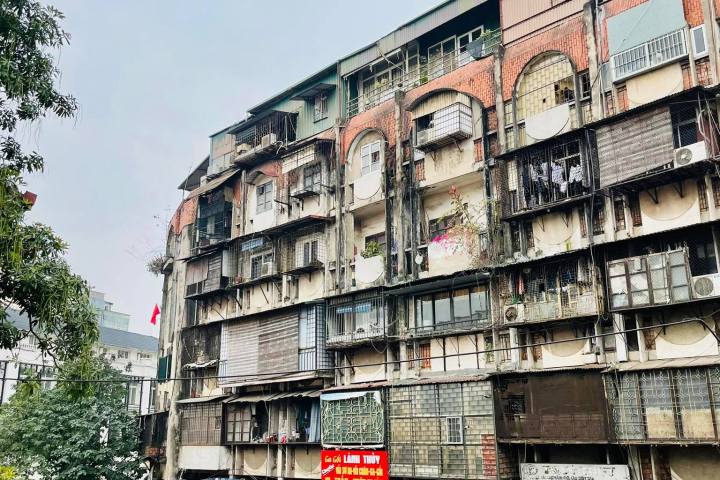 a group of people walking down a street next to tall buildings