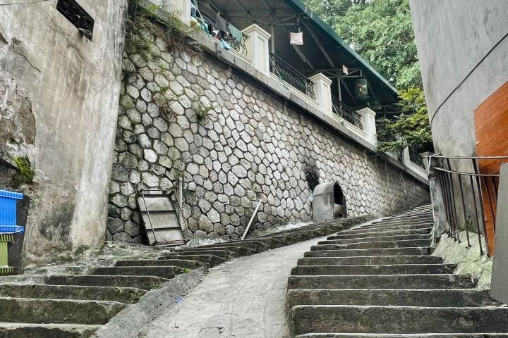 a person walking down a street next to a stone wall