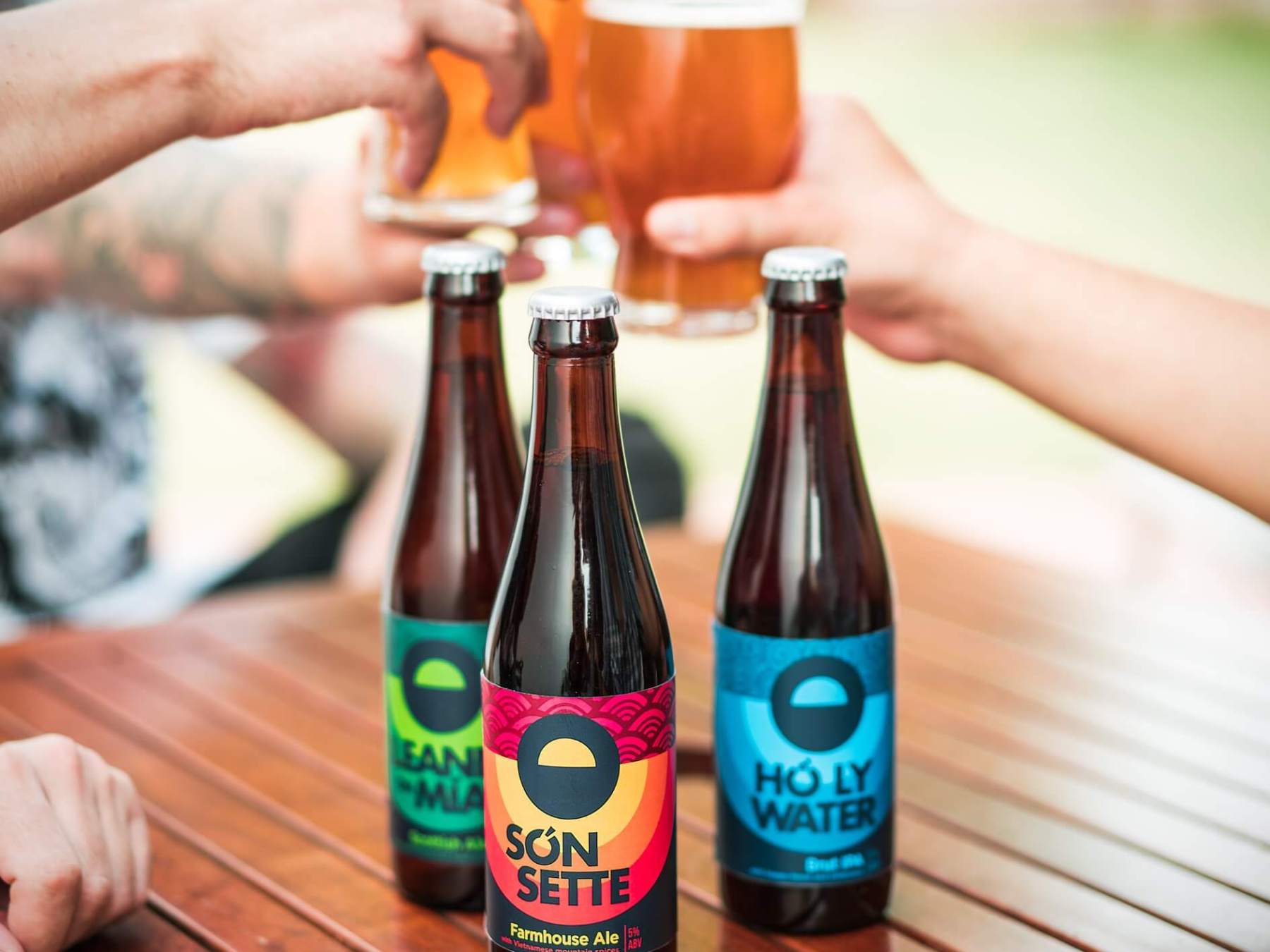 a hand holding a bottle of beer on a table