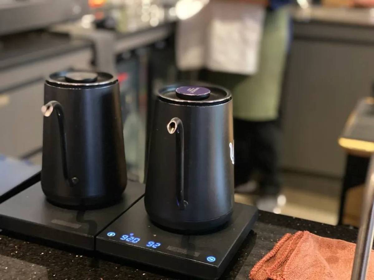Two black electric kettles on a counter with digital displays showing temperature.