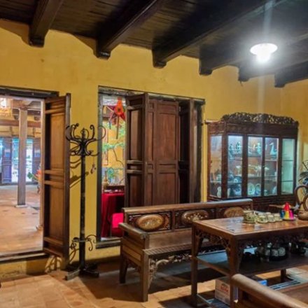 Traditional room with wooden furniture, display cabinet, and red wall scroll.