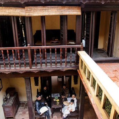 Aerial view of people sitting in a courtyard of a traditional house with wooden balcony.