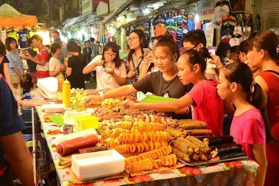 People buying and selling street food at a bustling market stall.