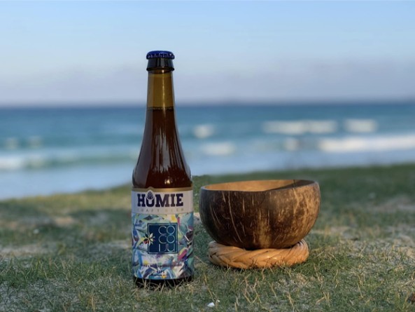 Bottle of drink and coconut bowl on grass by the sea.