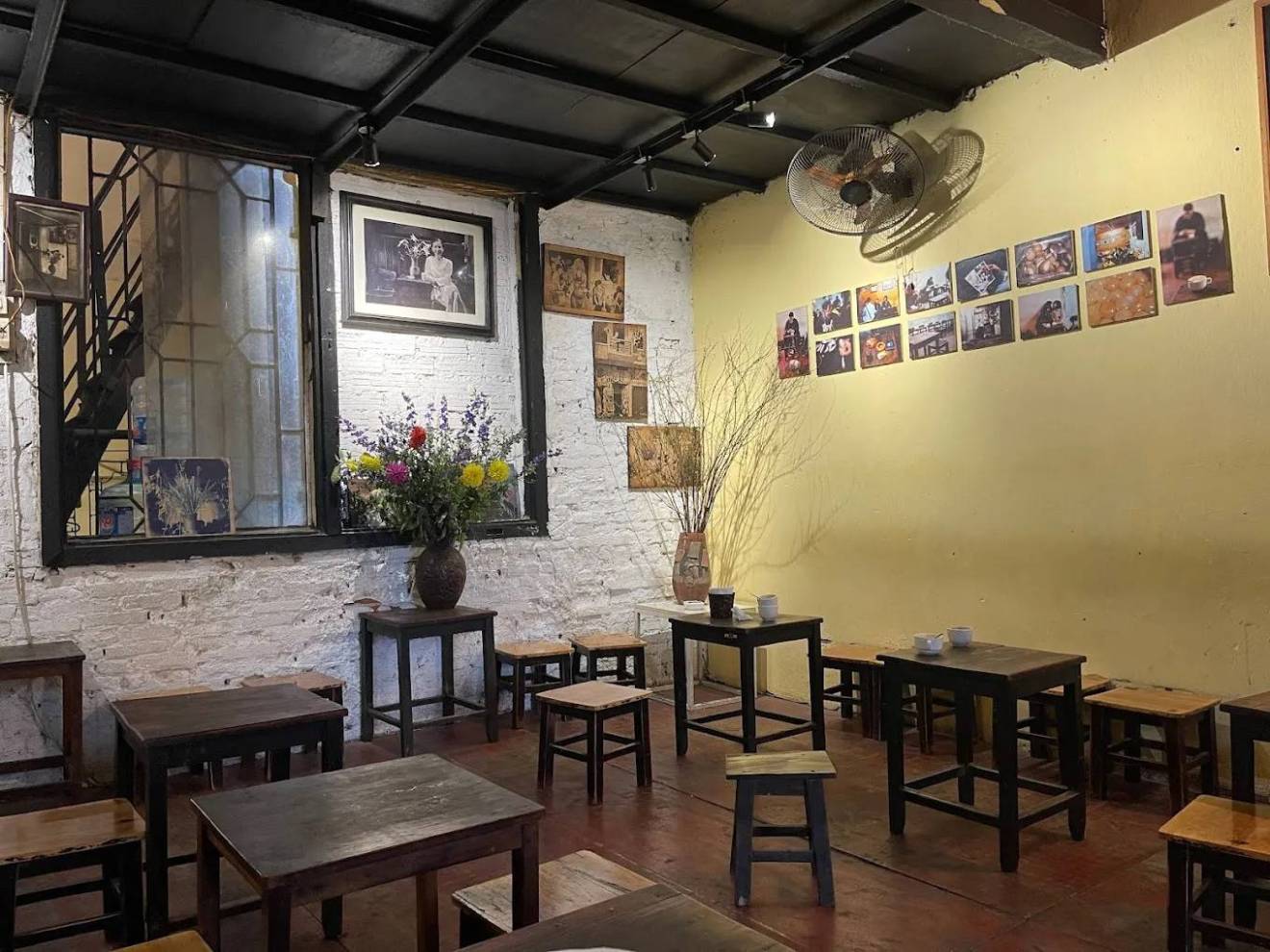 Cozy cafe interior with small wooden tables, stools, and wall art.