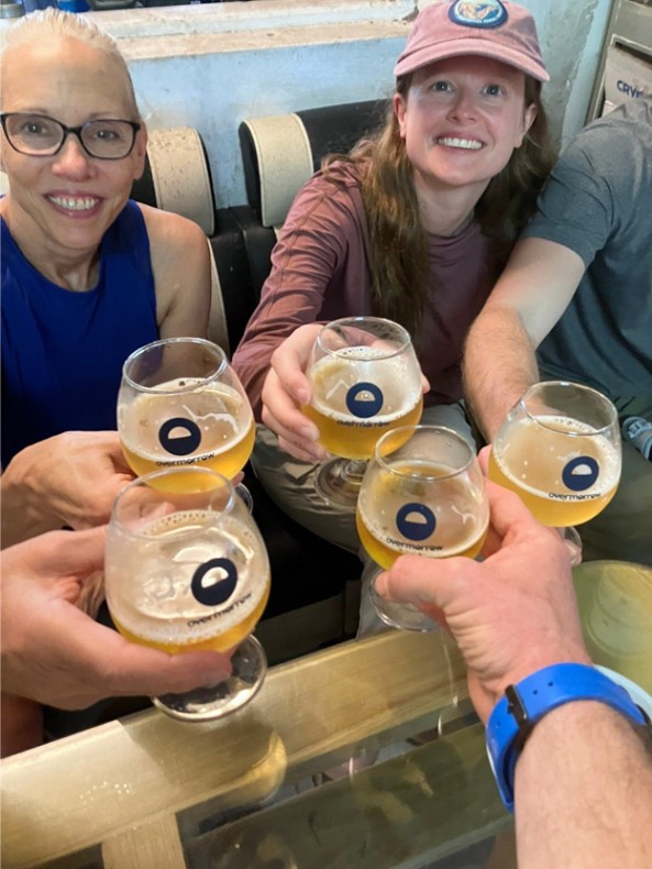 Group of people cheering with glasses of beer around a table.