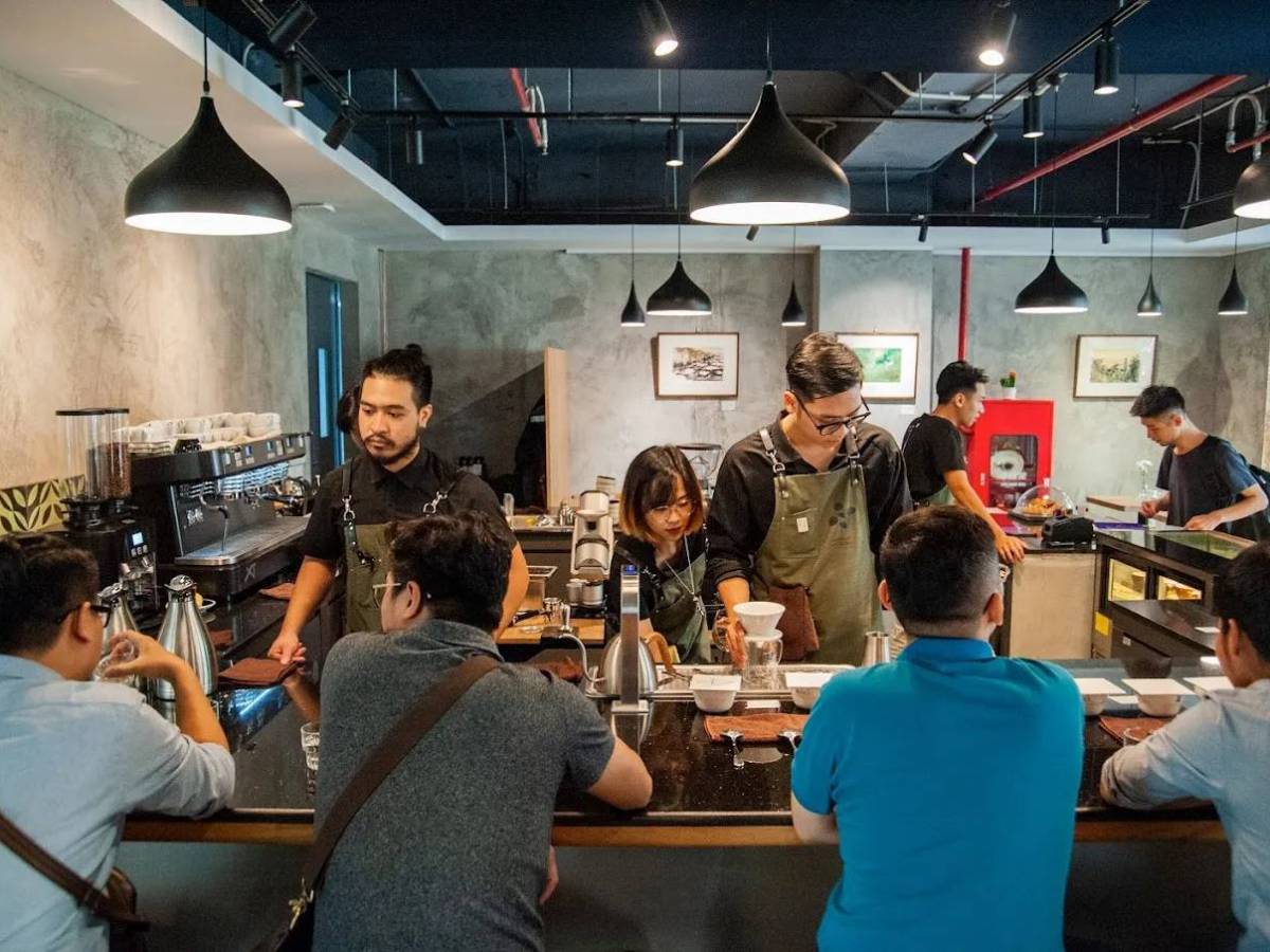 Baristas preparing coffee for customers sitting at a counter in a modern cafe.