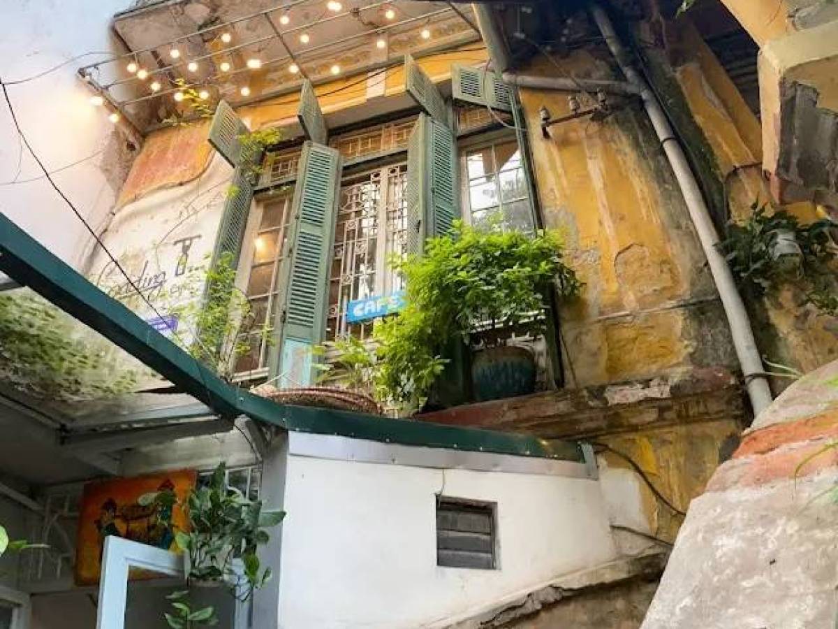 Old staircase leading to a rustic building with open shutters and greenery.