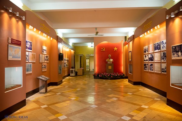 Museum corridor with a bust statue and communist symbols on a red wall.