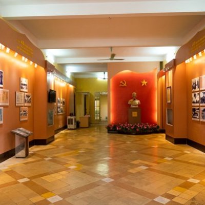 Museum corridor with a bust statue and communist symbols on a red wall.