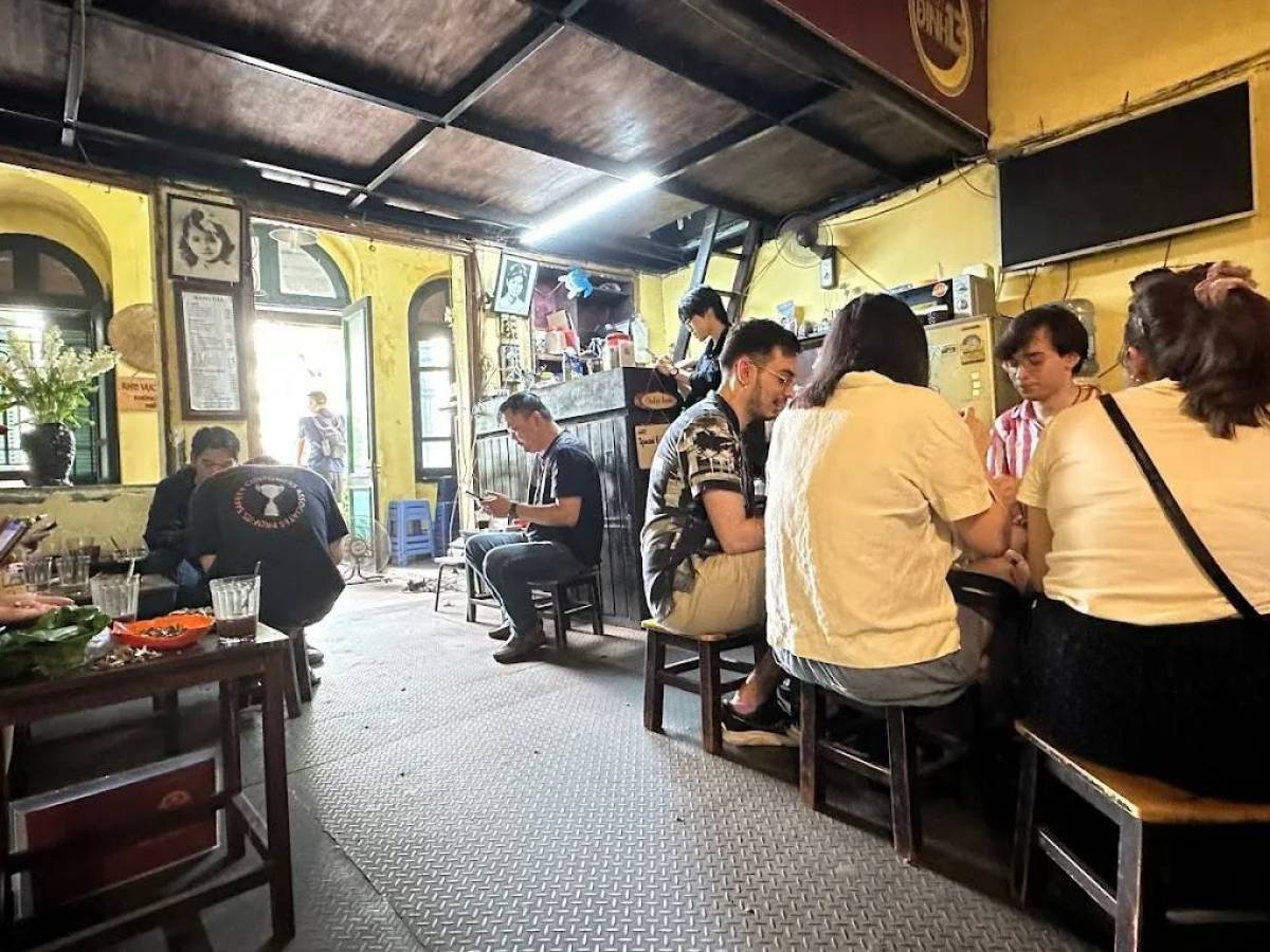 People sitting at tables inside a cozy café with yellow walls.