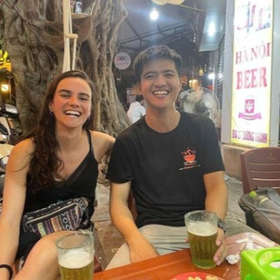 Two people smiling at an outdoor cafe table with drinks.