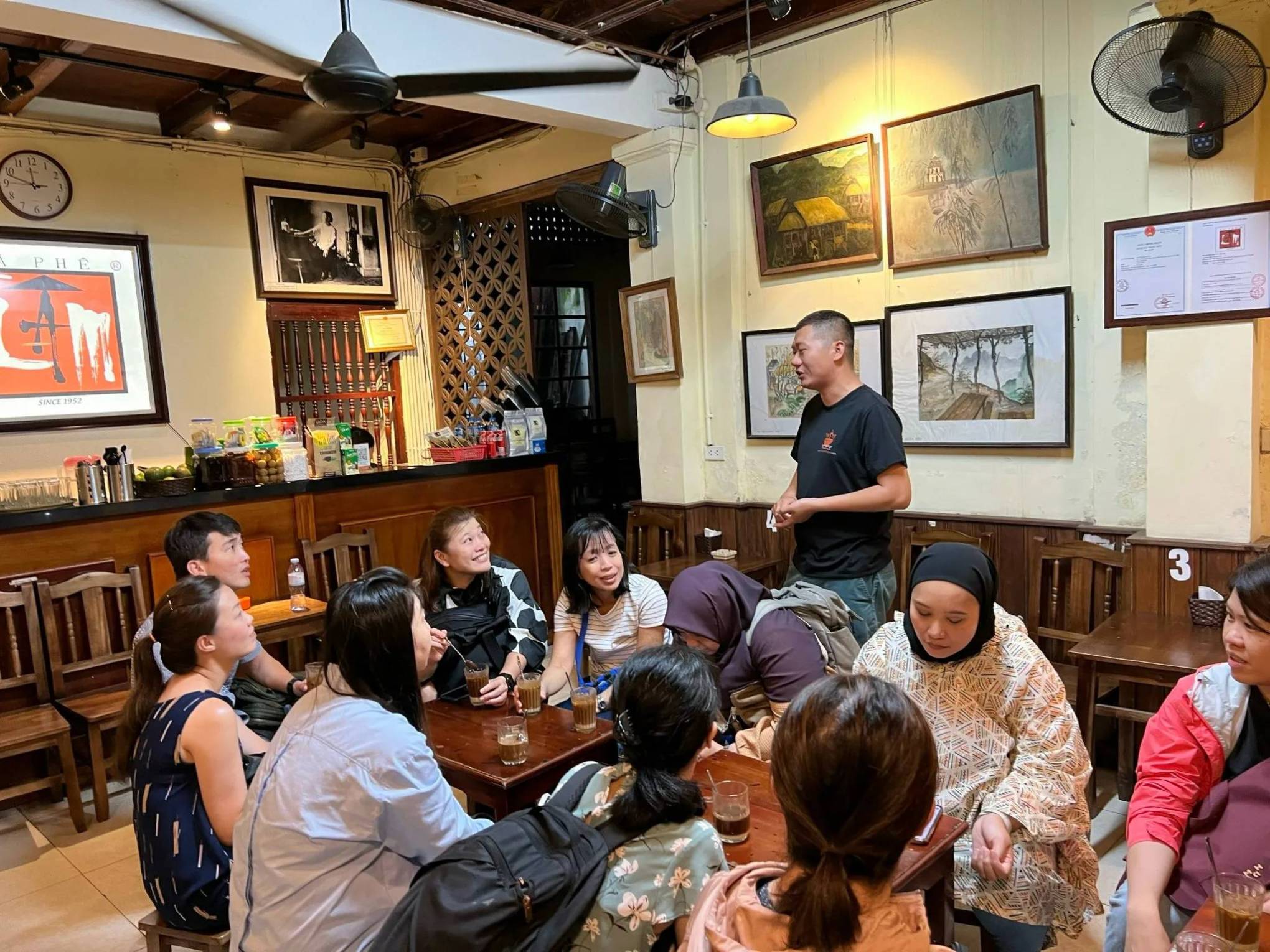 People gathered in a cozy cafe with art on the walls, engaged in conversation.