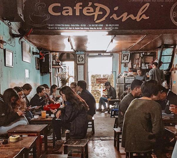 People seated at tables in a cozy café with dim lighting and rustic decor.