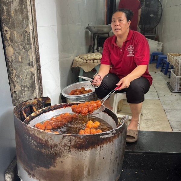 Person frying food balls in a large pot of oil in a small kitchen.