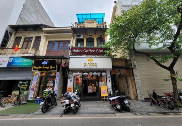 Street view of Hanoi coffee shop with parked scooters and spa signs.