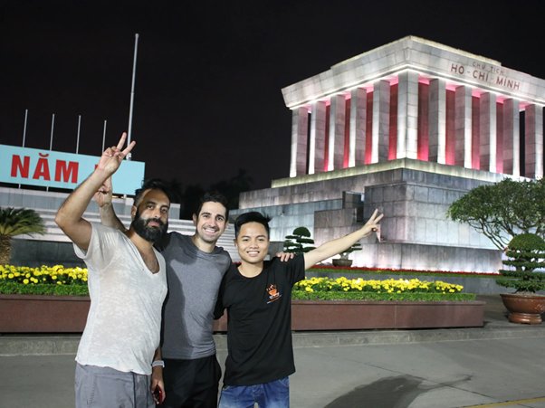 Three people pose in front of a lit-up building at night.