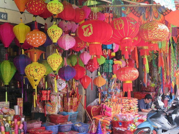 Colorful lanterns hanging in a busy market stall filled with festive decorations.