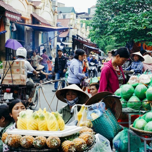 Bustling street market with vendors, produce, and people walking in Vietnam.