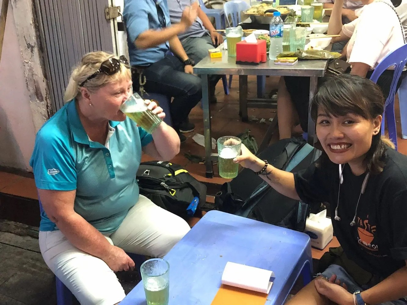Two people drinking beverages at a small outdoor table.