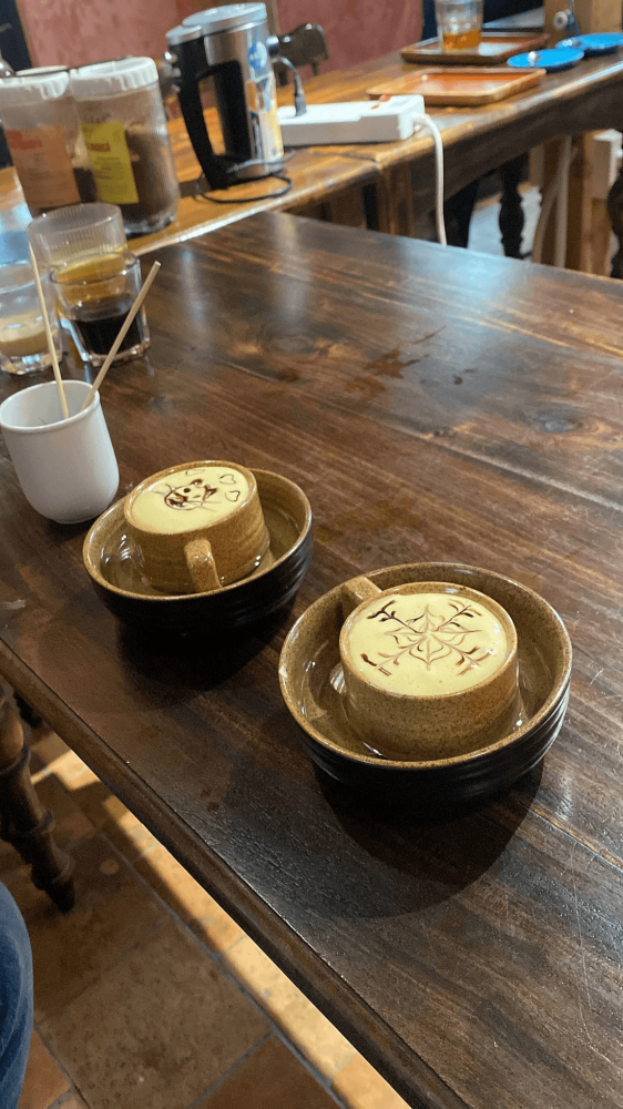 Two cappuccinos with latte art on a wooden table.