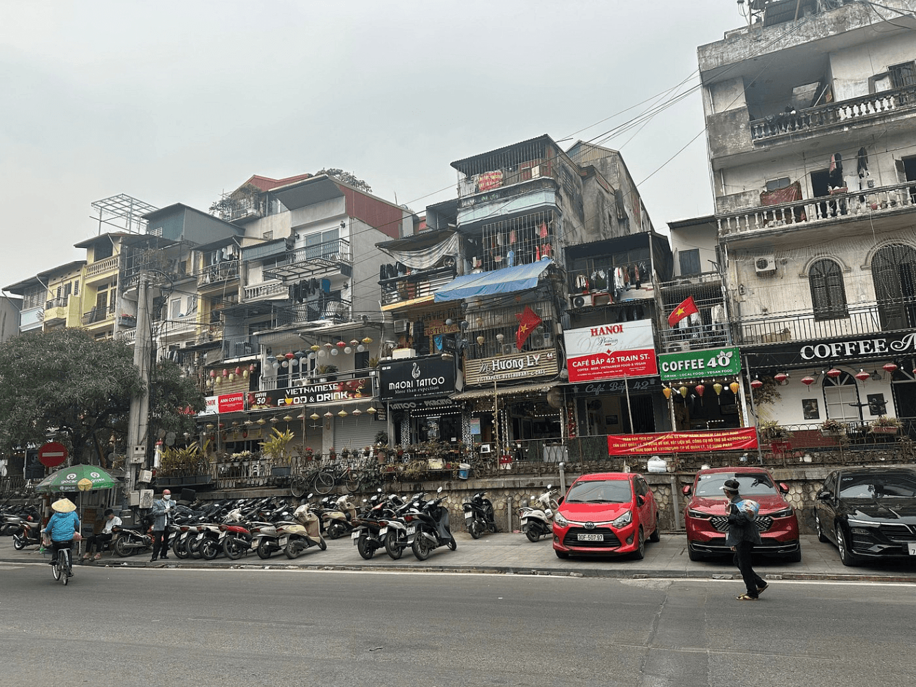 Street scene with parked motorbikes, cars, and multi-level buildings with signs.