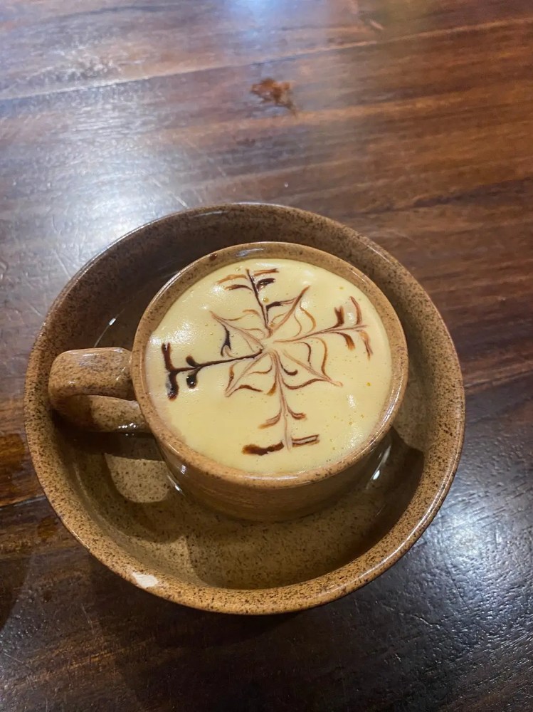 Latte art with a tree design in a brown cup on a wooden table.